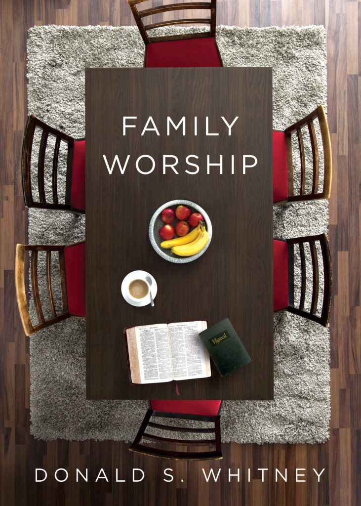 Book cover for Family Worship by Donald S Whitney. It shows a table from the top with 6 chairs around it. There is a bowl with apples and bananas on it as well as a cup of tea and a Bible.