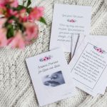 labor and delivery cards. It depicts the cards spread out on the white table cloth with the pink flowers beside them.