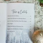 Great Hymns for Growing Hearts - Christmas Edition. The book is open to the table of contents. It is laying on a furry, white rug with a candle and evergreens around it.