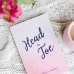 Head to Toe Prayer Journal. The pink edition of the book is laying on a white cloth with flowers and coffee nearby