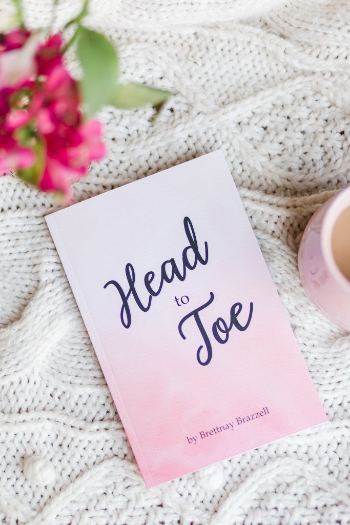 Head to Toe Prayer Journal. The pink edition of the book is laying on a white cloth with flowers and coffee nearby