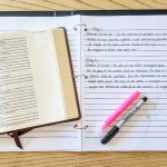 Open notebook with scripture written under daily headings shown with an open Bible, a highlighter, and a pen