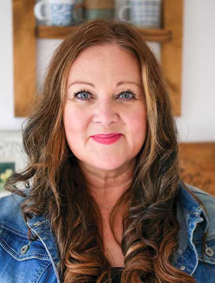 Profile image of Leah Boden. She is in a kitchen and wearing a jean jacket with her long brown hair hanging over her chest.