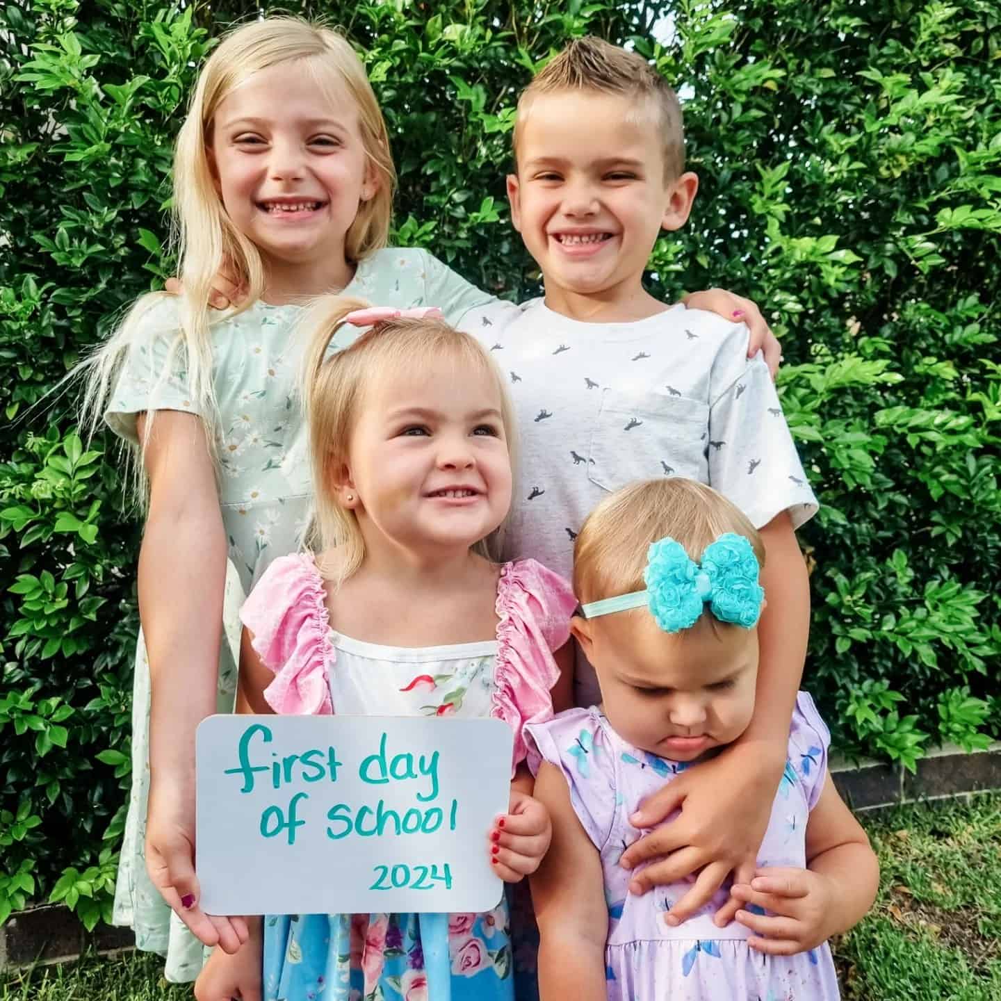 Brazzell kids in front of a bush. They are holding a sign that says "first day of school 2024"