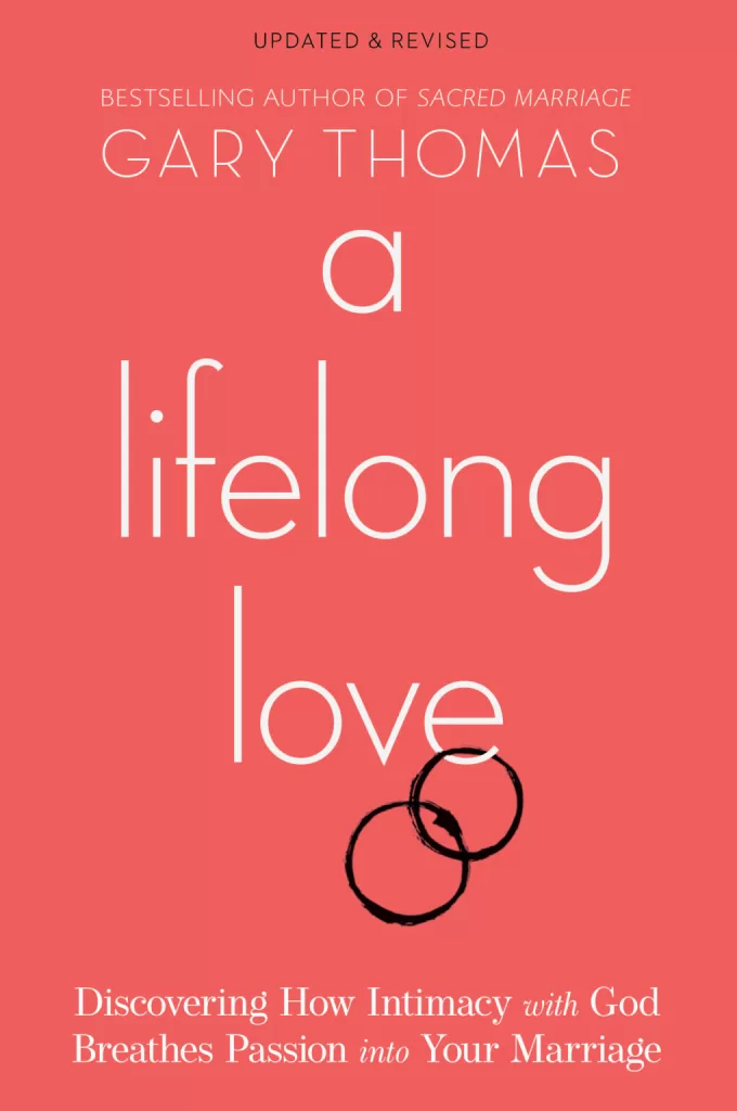Book Cover for "A Lifelong Love" by Gary Thomas. It has a pinkish red cover with two wedding rings hanging off of the "e" of the word "love".