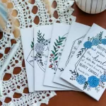 Five Friendship Cards flayed out on a wooden table that is covered in lace with 2 pens beside them.