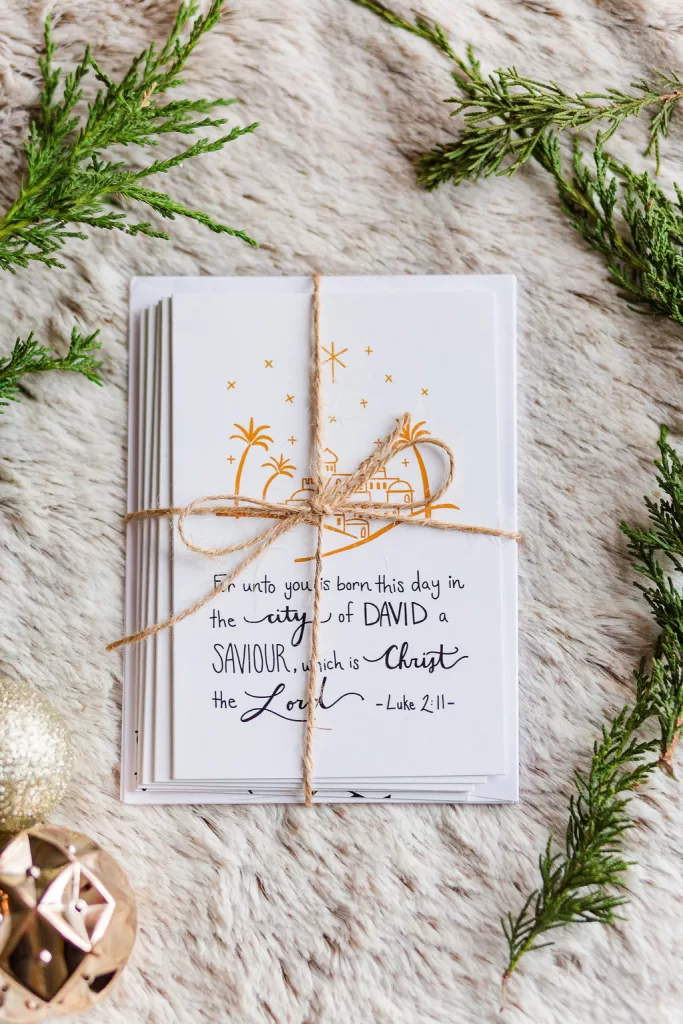 Beautiful Christmas Cards wrapped in a twine bow and laid on soft fir with pine branches around it.